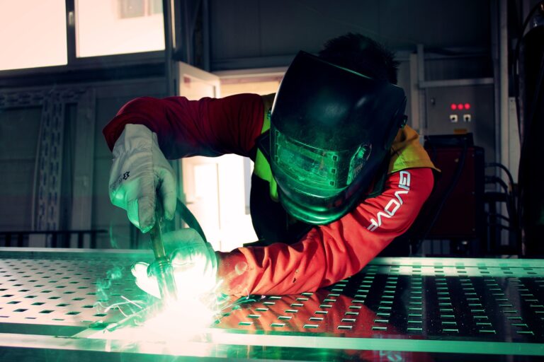 A welder working on a table, wearing black stallion fr welding shirt