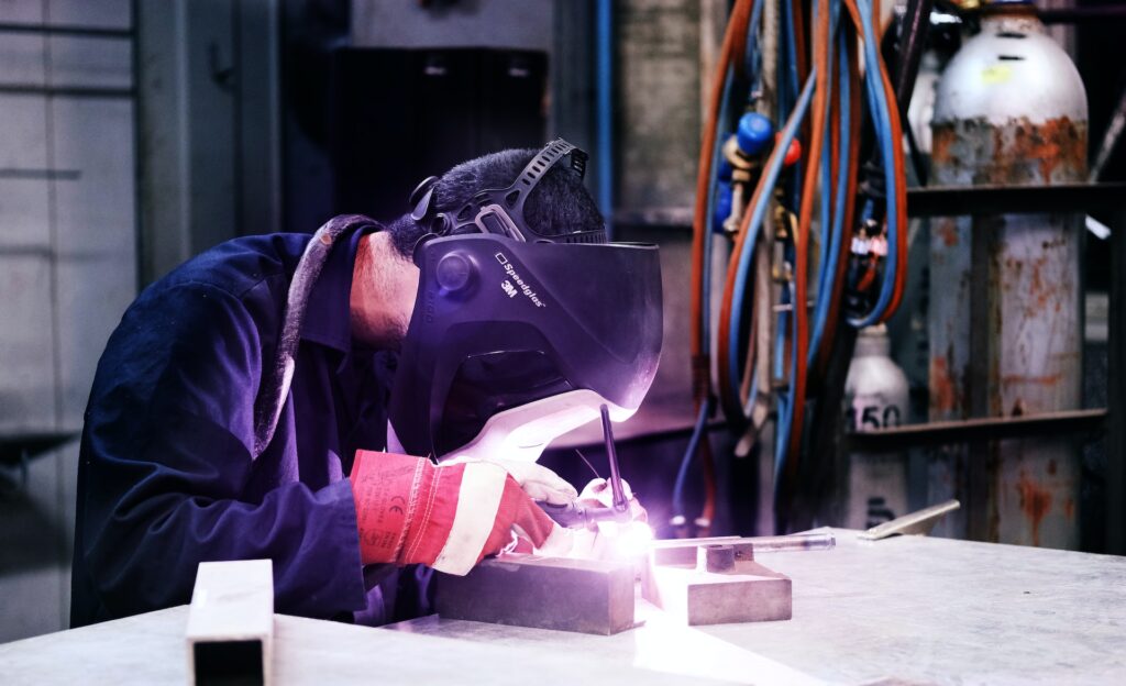 welders dress in blue work clothes, wearing a blue pearl snap shirt